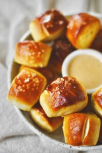 Homemade Pretzel Bites on a platter with cheese sauce in the middle for dipping.