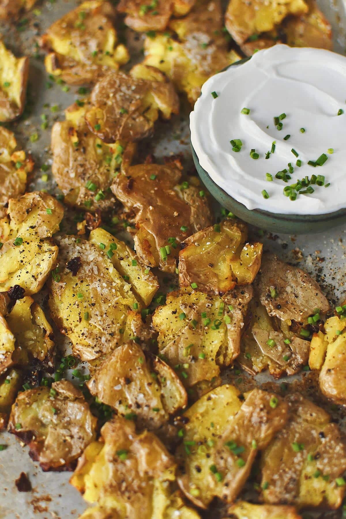 Crispy Smashed Potatoes just out of the oven ready to be enjoyed with some chive sour cream on the side.