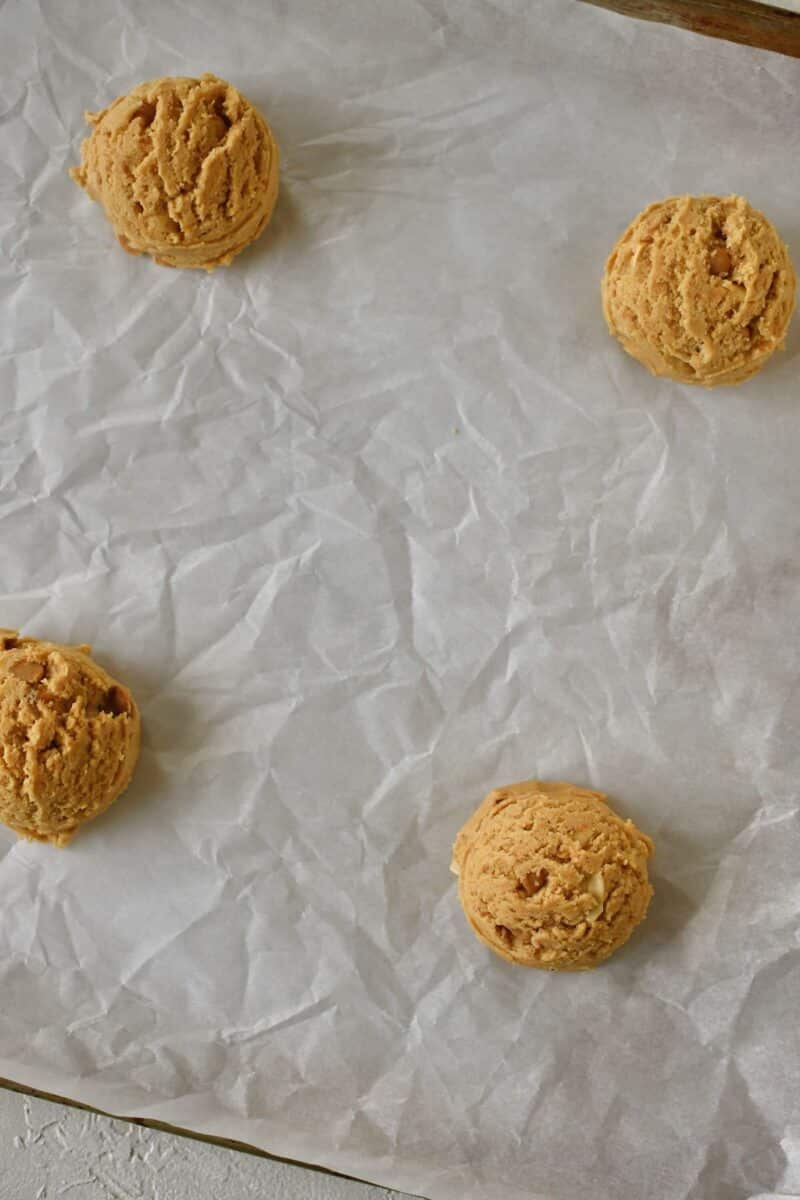 Portioned cookie dough on a parchment lined sheet pan.