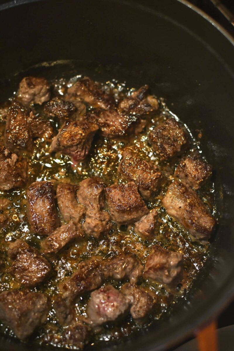 Searing the steak pieces in a deep pot in the butter and oil.