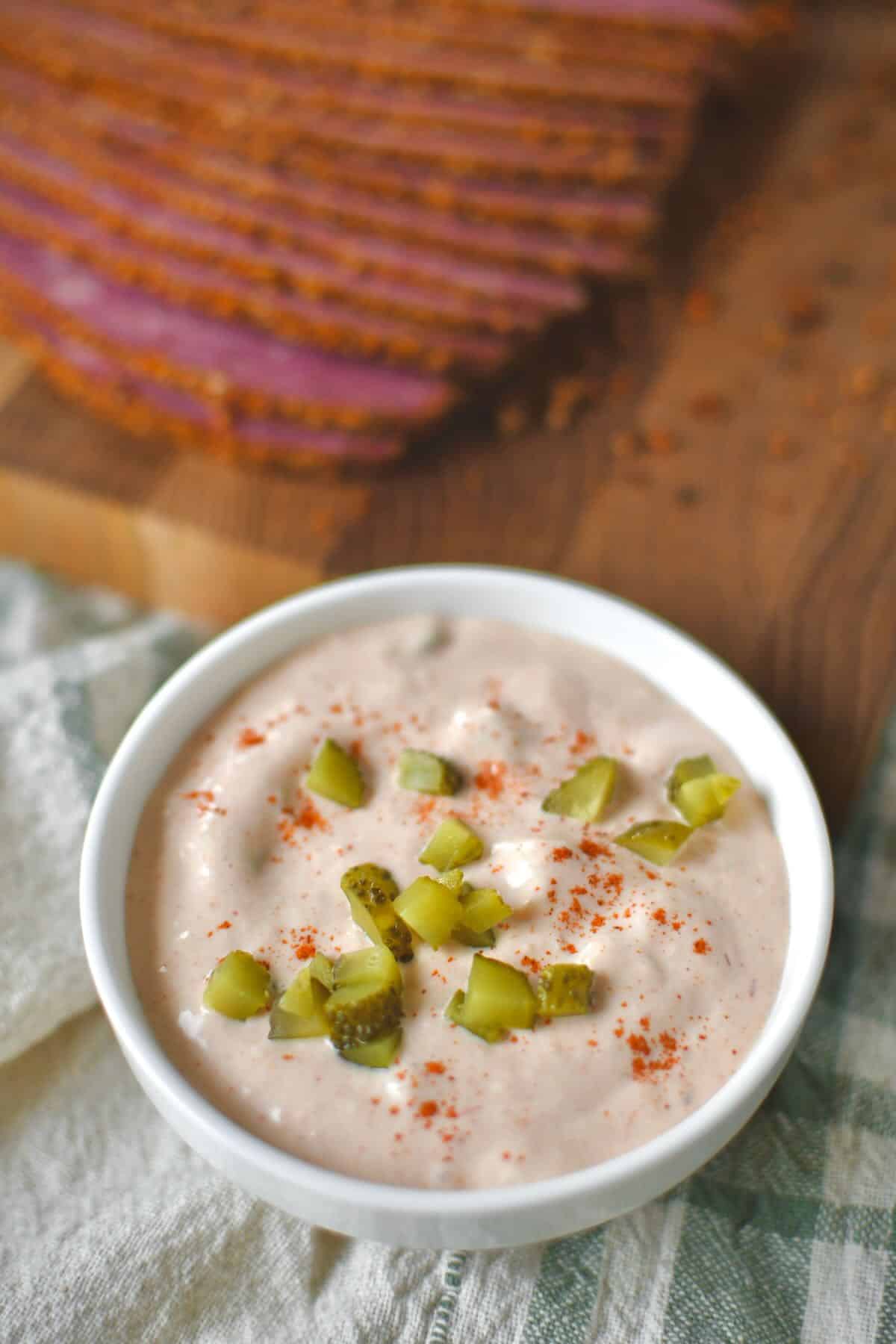 Complete Russian dressing recipe in a bowl topped with a sprinkle of paprika and chopped pickles.