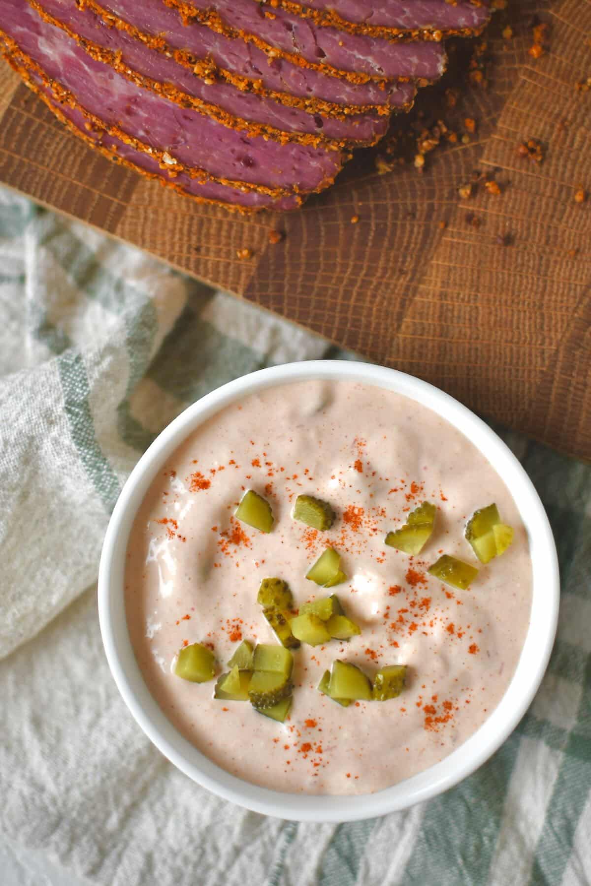 Complete Russian dressing recipe in a bowl topped with a sprinkle of paprika and chopped pickles.