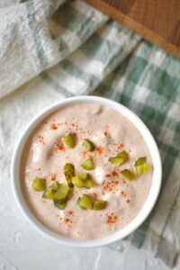 Complete Russian dressing recipe in a bowl topped with a sprinkle of paprika and chopped pickles.