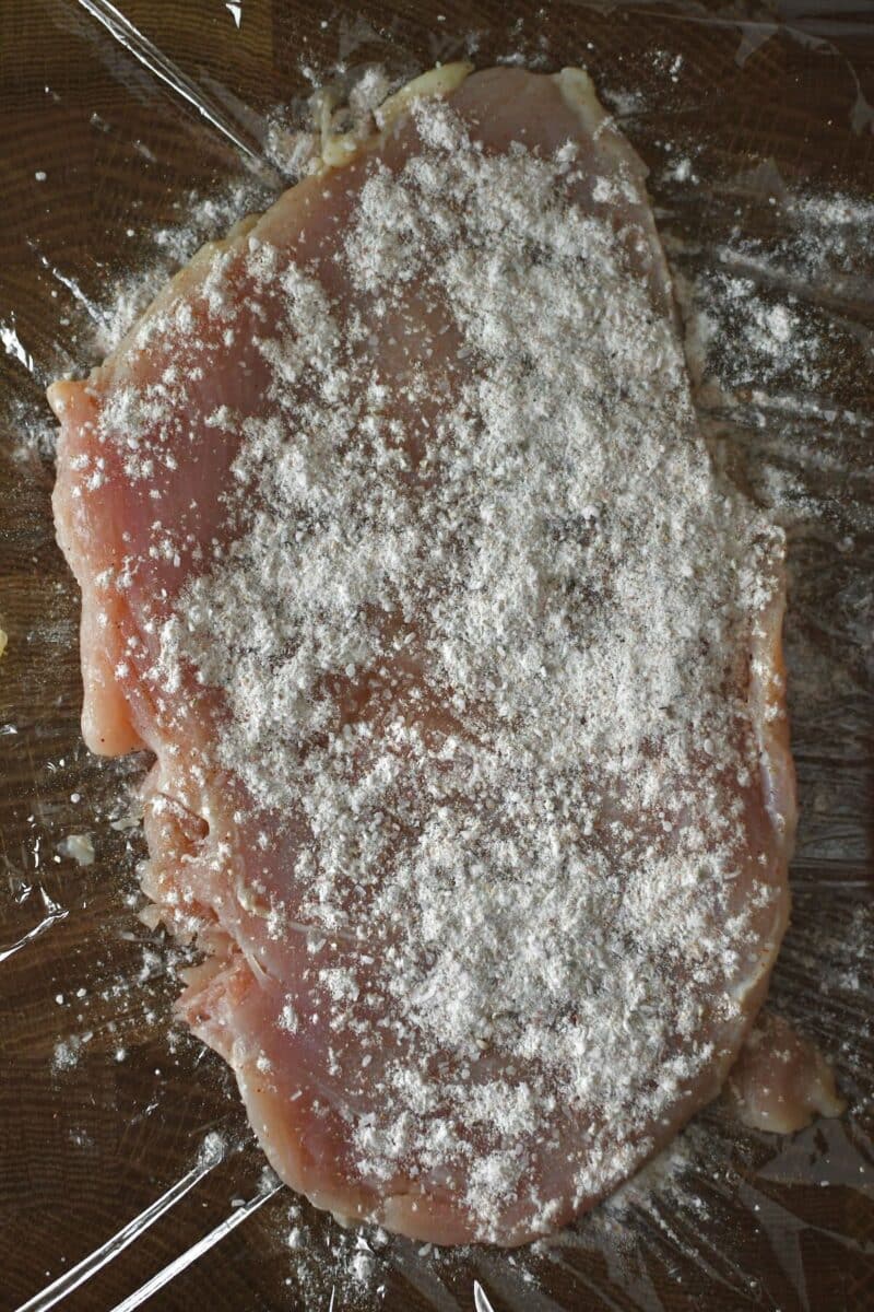 Tenderized chicken, seasoned spiced flour, ready to be seared.