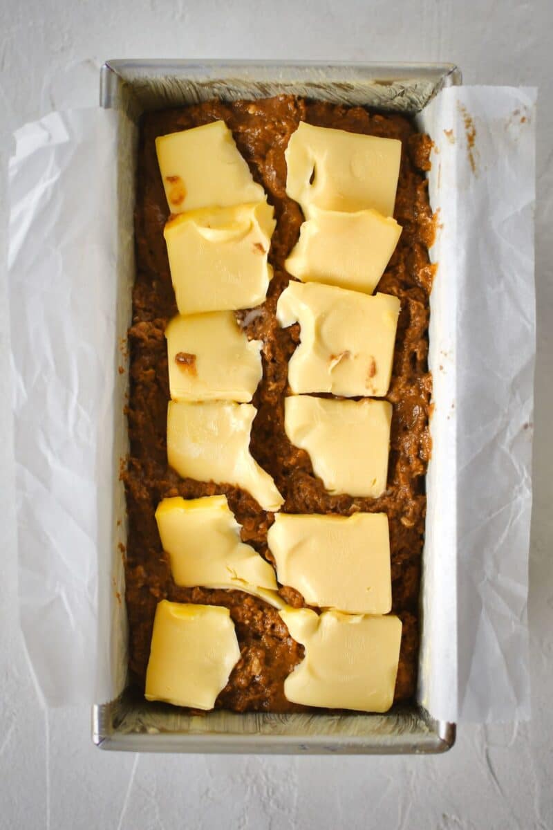 Topping the unbaked bread with butter before baking.