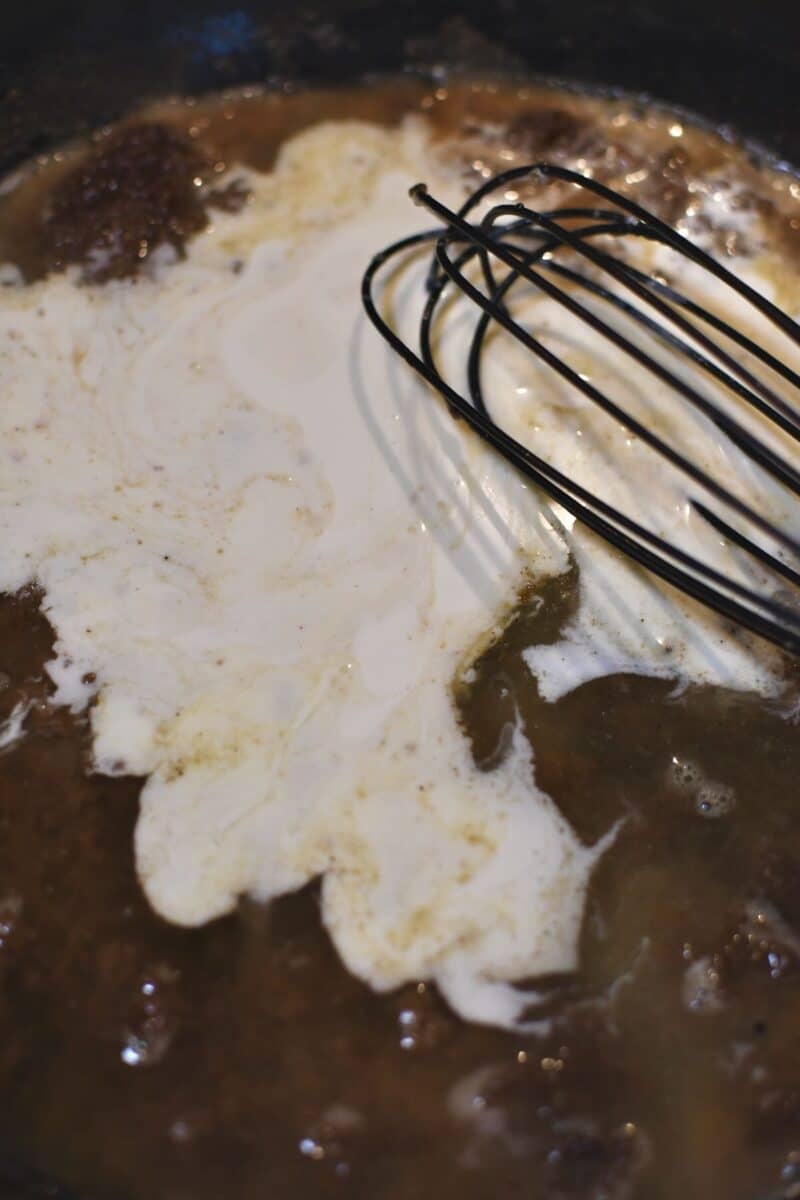 Adding the cream and stock to the pan to form the sauce.