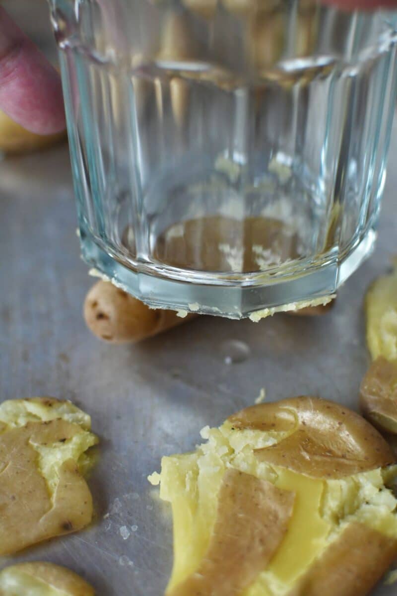 Smashing the potatoes on a tray with a sturdy glass.