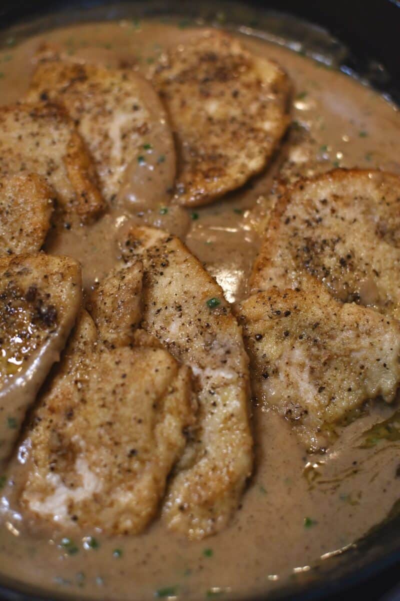 Placing the seared chicken back in the pan to finish cooking and marry with the sauce.