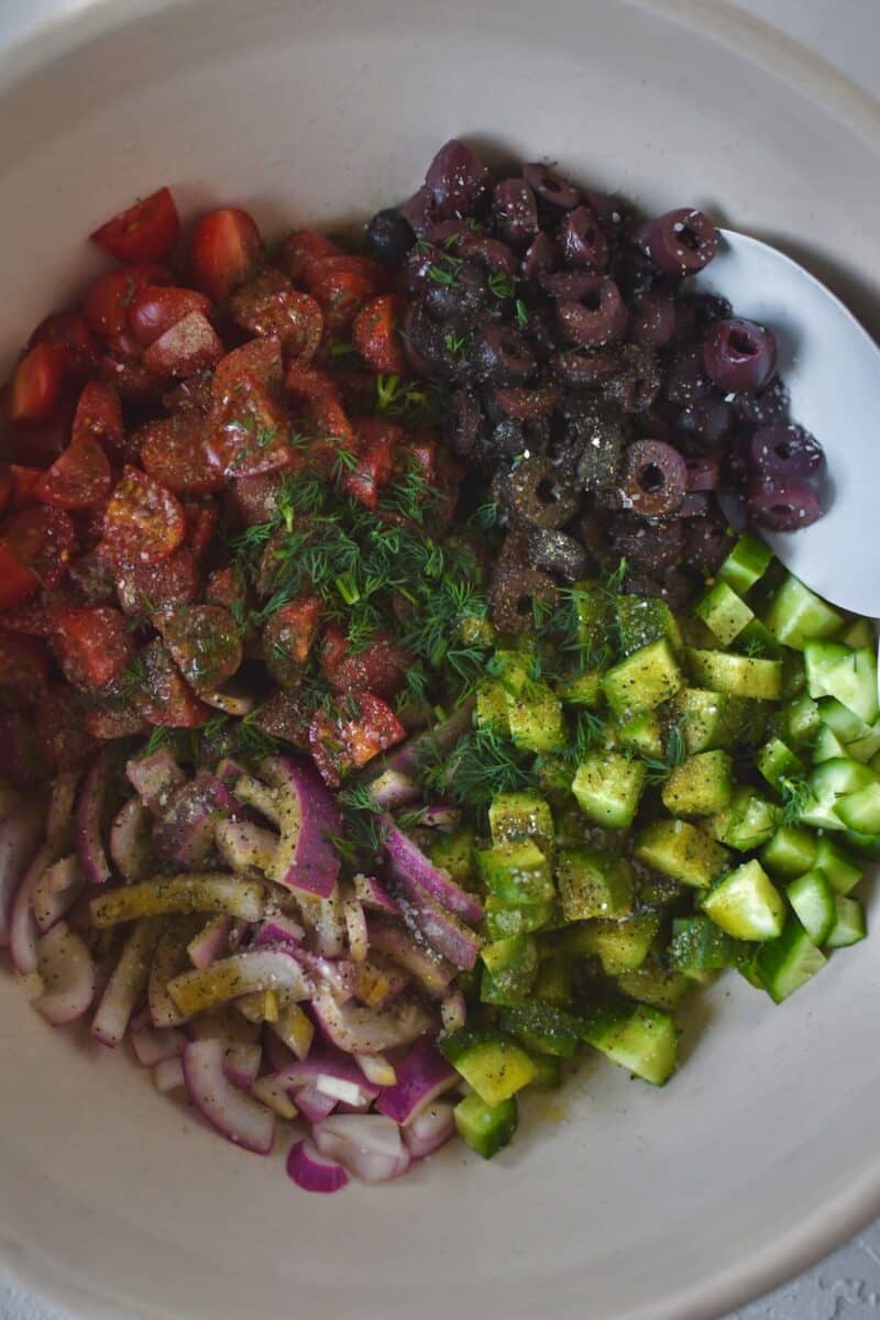 Adding the other veg to the bowl with the tomatoes and seasoning them.