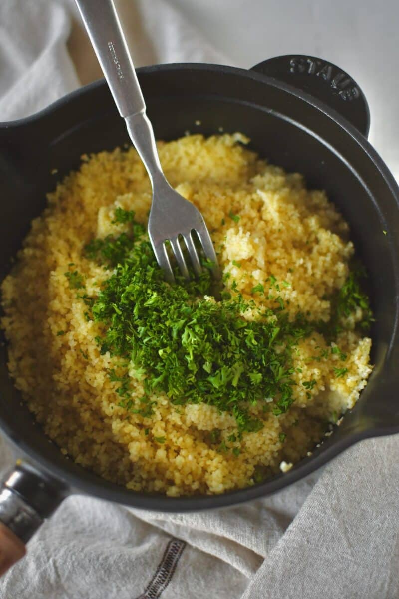 Cooked couscous, using a fork to fluff it and fold in some parsley.
