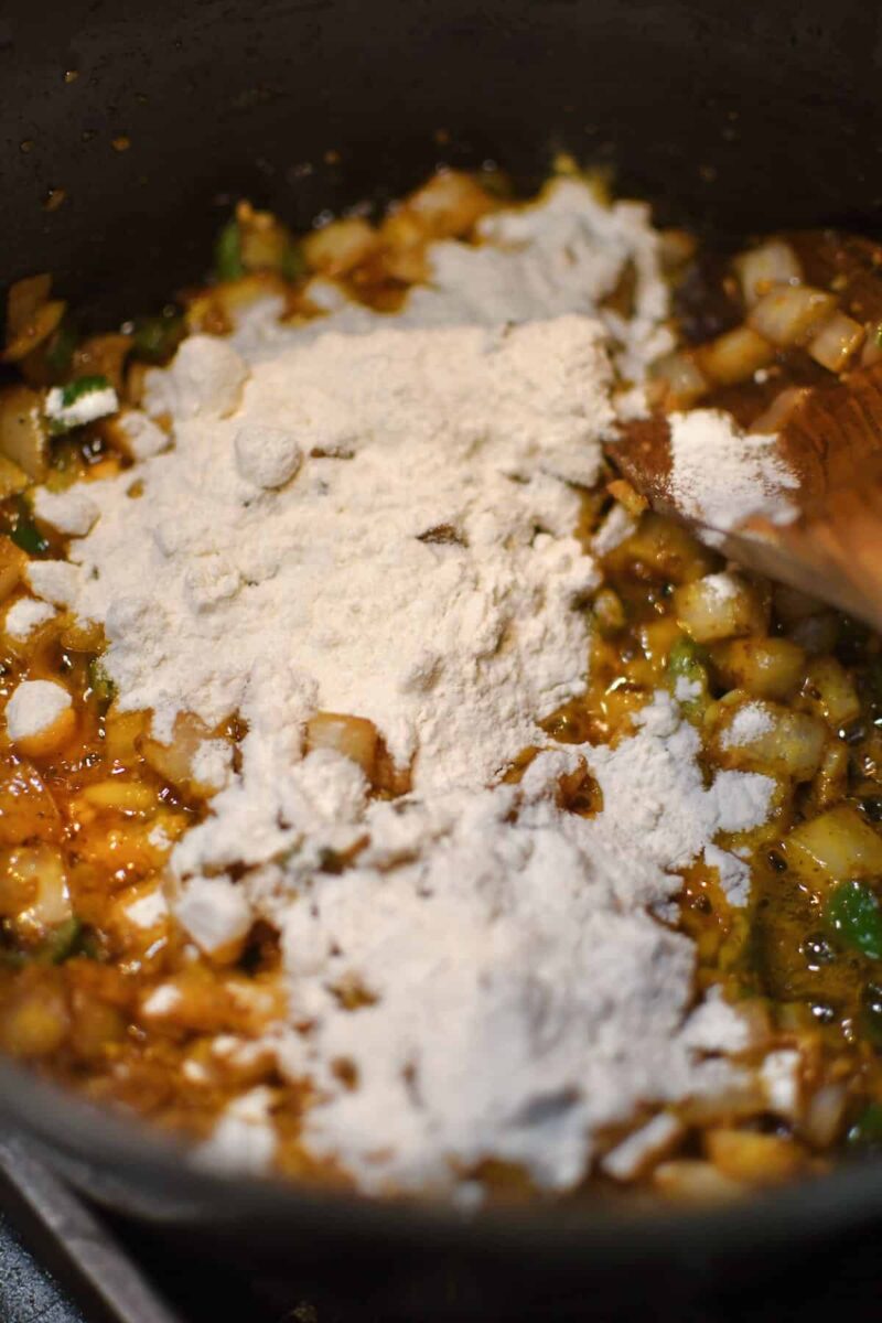 Dusting the soup base with the flour to form a roux and thicken the soup.