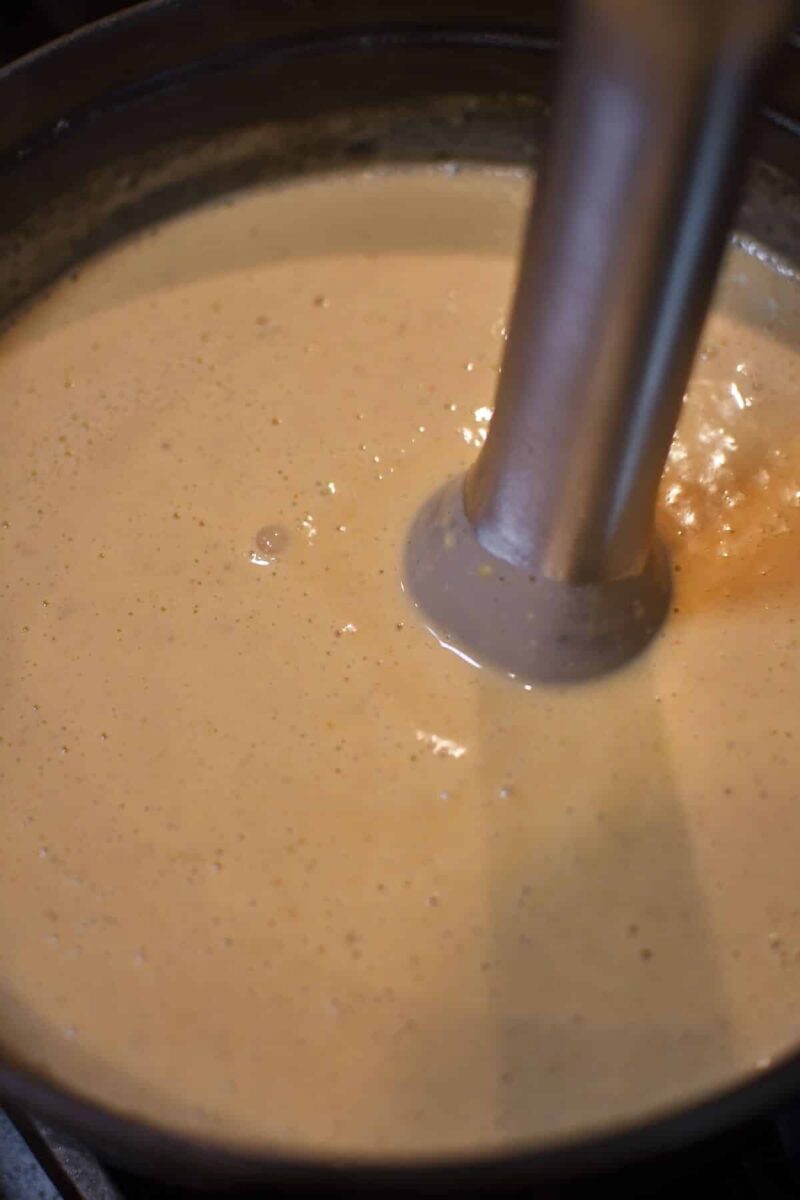 Blending the cheese into the soup to make it smooth.