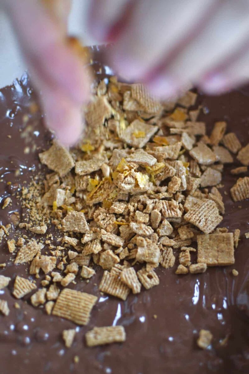 Crushing golden graham cereal into the melted chips and peanut butter mixture.