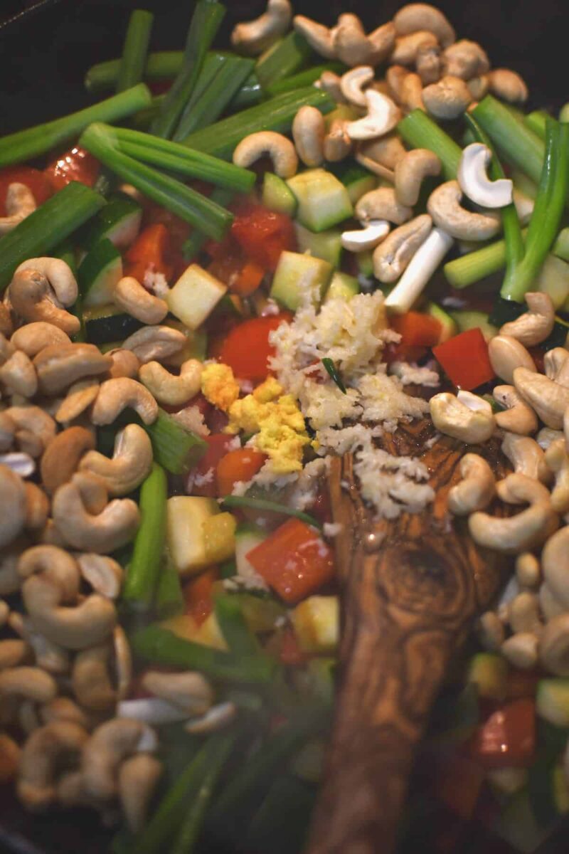 Adding the aromatics and cashews to the pan to toast before adding the chicken and sauce in.