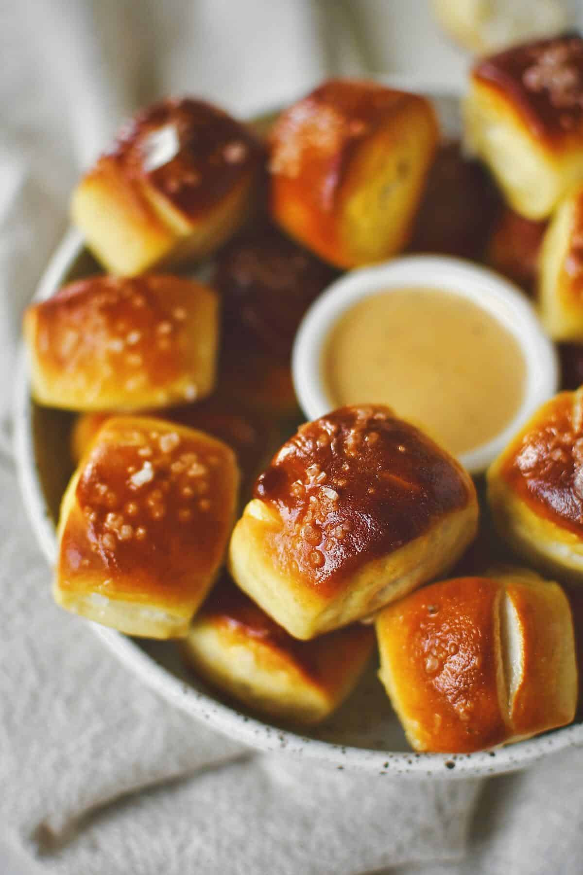 Homemade Pretzel Bites on a platter with cheese sauce in the middle for dipping.