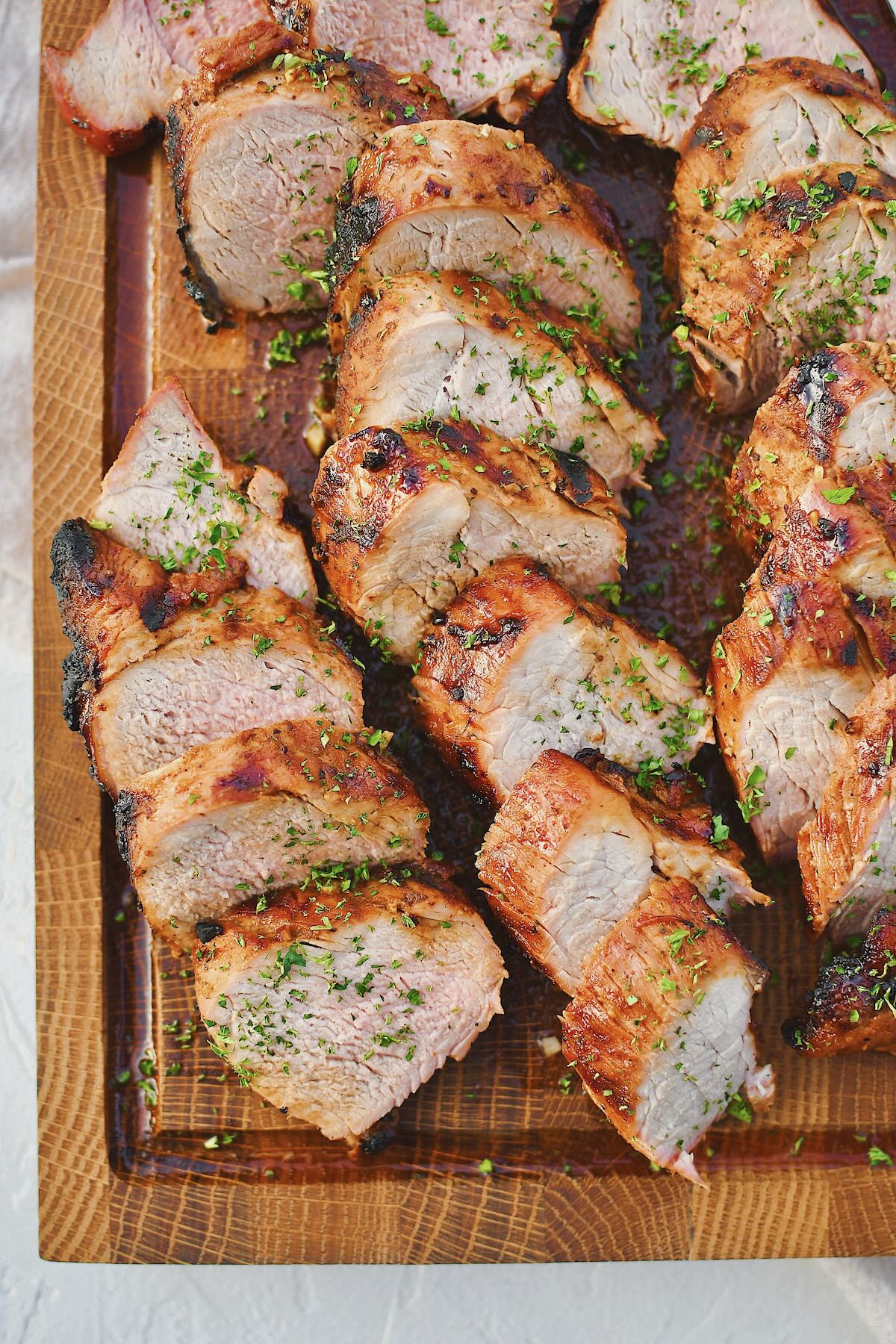 Grilled Pork Tenderloin sliced and resting on a cutting board with the knife on the side.