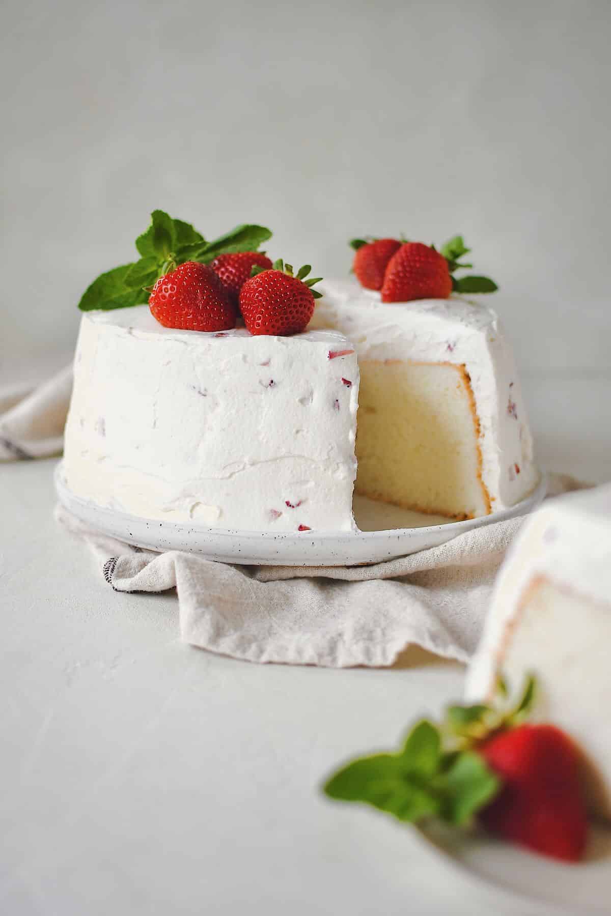 Strawberry Angel Food Cake with a single slice cut out of it.