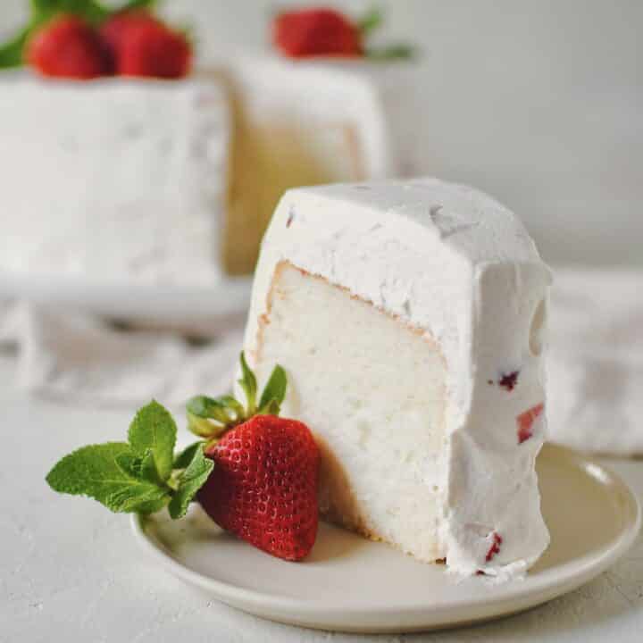 Strawberry Angel Food Cake with a single slice cut out of it.