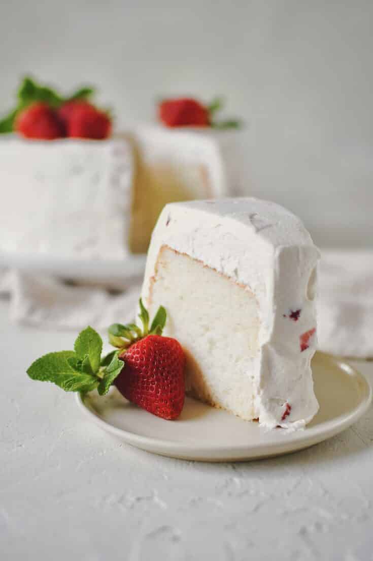 Strawberry Angel Food Cake with a single slice cut out of it.