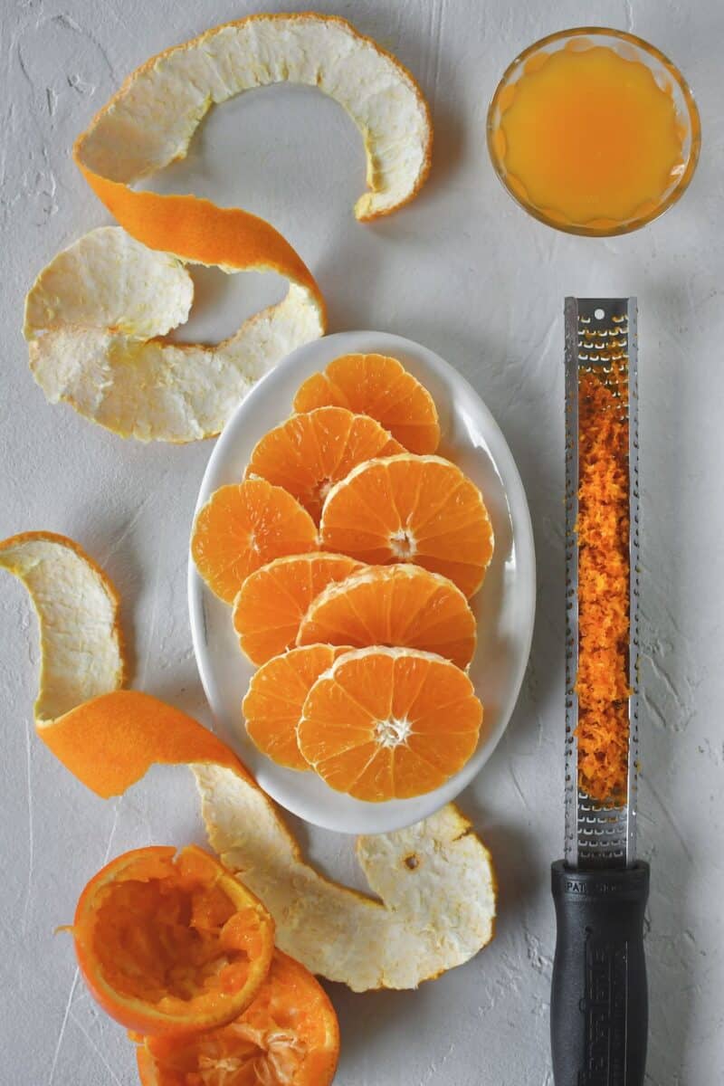 Prepared tangerines, two that have been zested, peeled, and sliced, 1 that has been juiced.