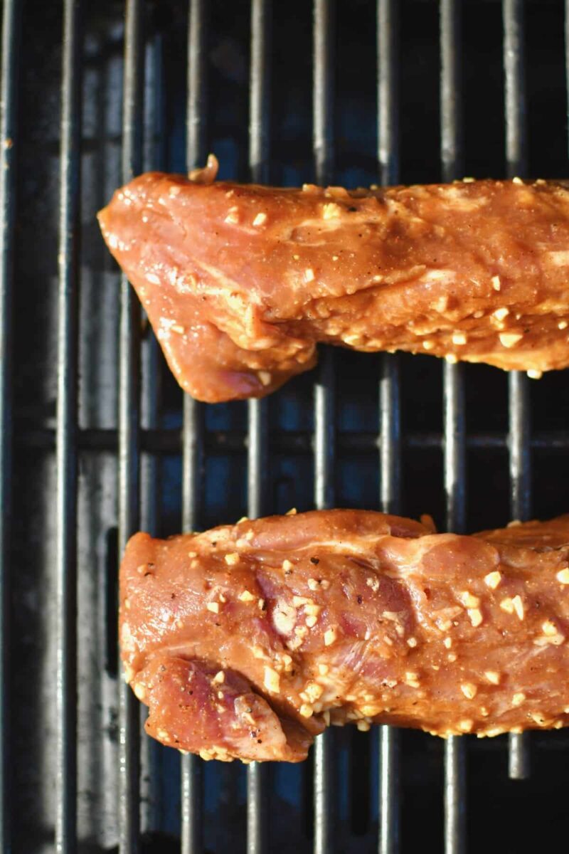 Marinated pork tenderloins just out of the marinade and placed on a hot grill.