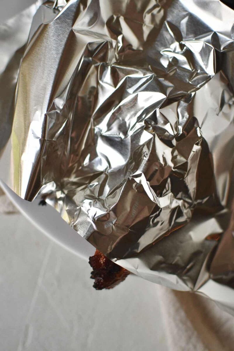 Pork Tenderloins resting under a piece of tin foil before slicing and serving.