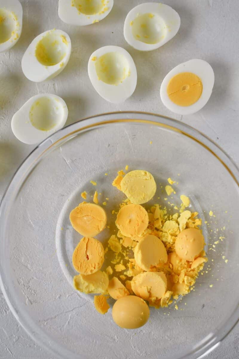 Boiled eggs that have been cut in half and the yolks removed to a bowl.