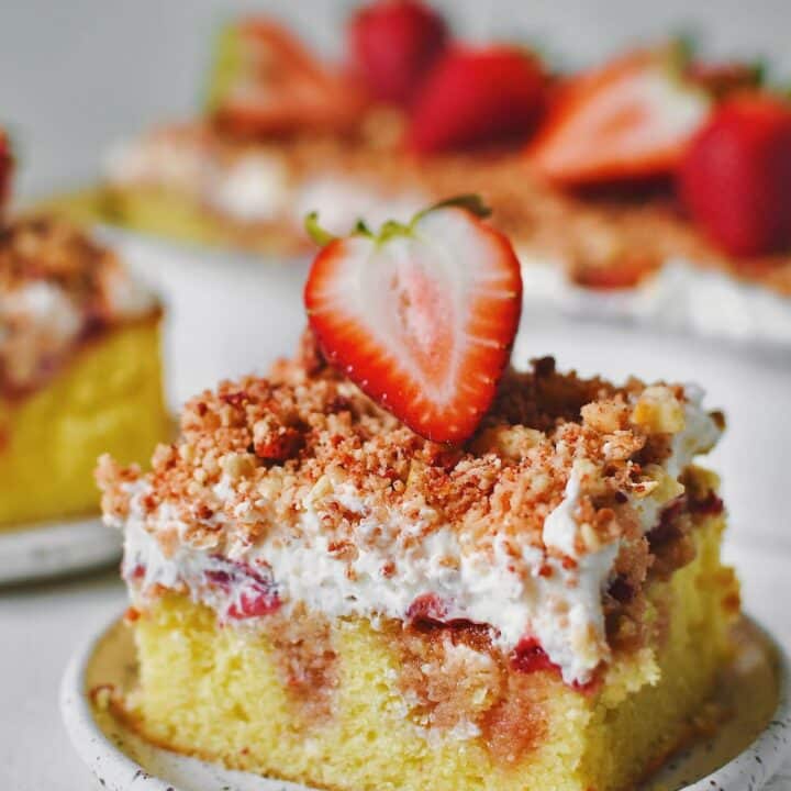 A slice of Strawberry Crunch Cake removed from the pan with a fresh strawberry on top.