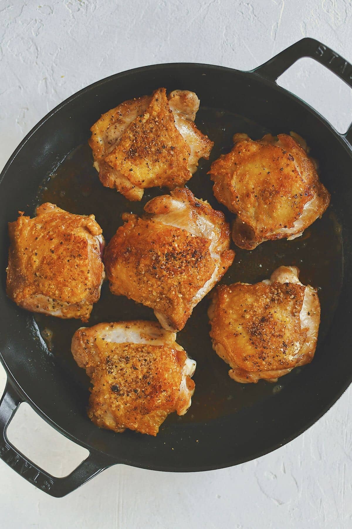 Perfectly crisped chicken thighs in a large skillet.