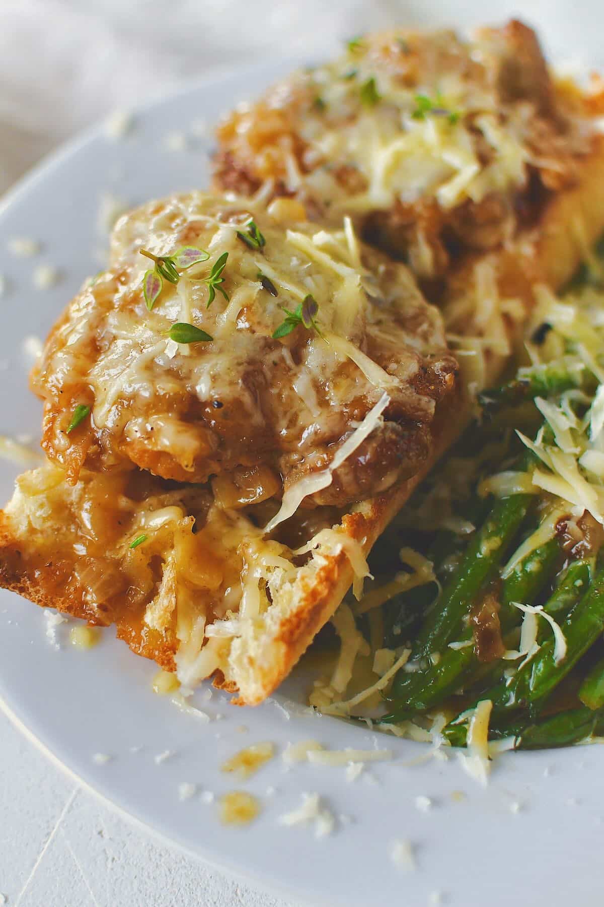 French Onion Chicken served over a piece of crusty bread to soak up the extra sauce and some sauteed green beans.