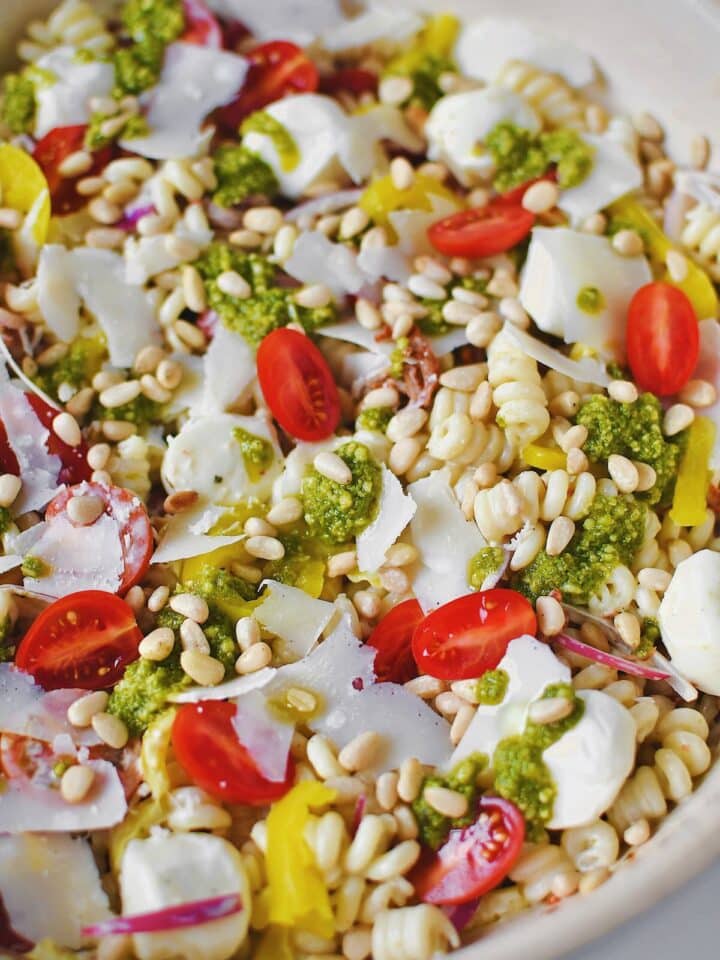 Fully dressed Pesto Pasta Salad topped with pesto and freshly shaved parmesan before serving.