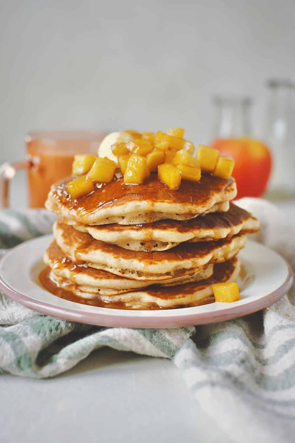 Apple Cinnamon Pancakes stacked up and topped with caramel apple syrup and butter.