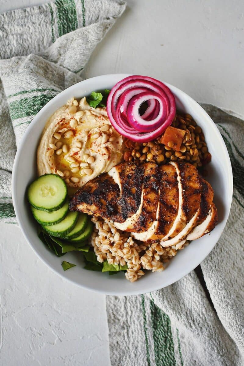 Cucumbers, pickled red onions, and chicken added to the bowl.