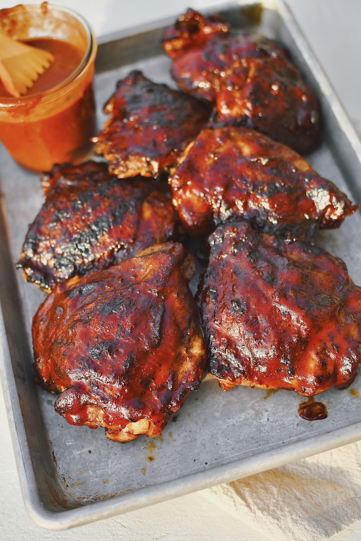 Grilled Chicken Thighs fresh off the grill and slathered in bbq sauce.