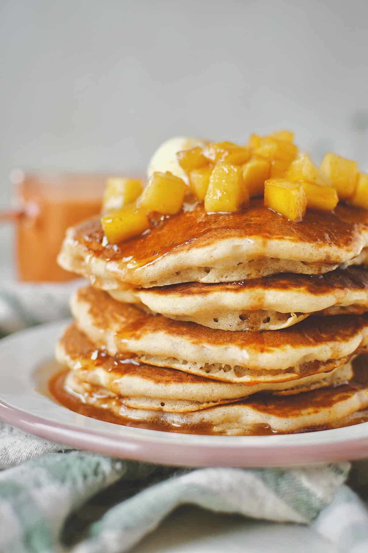 Apple Cinnamon Pancakes stacked up and topped with caramel apple syrup and butter.