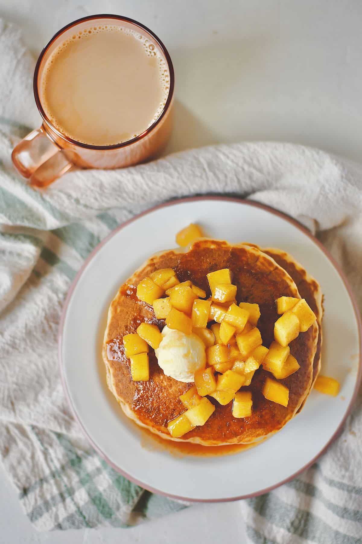 Apple Cinnamon Pancakes stacked up and topped with caramel apple syrup and butter.