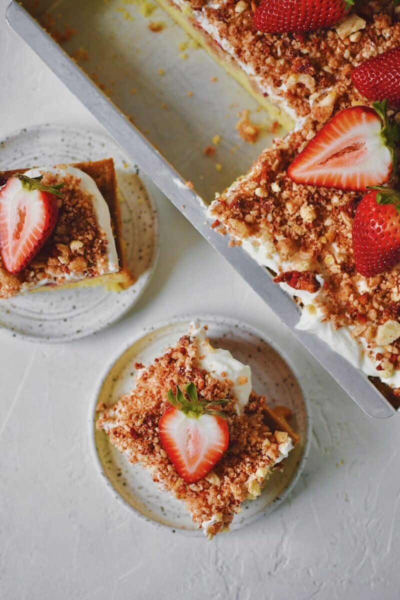 A couple slices of Strawberry Crunch Cake removed from the pan with a fresh strawberry on top.