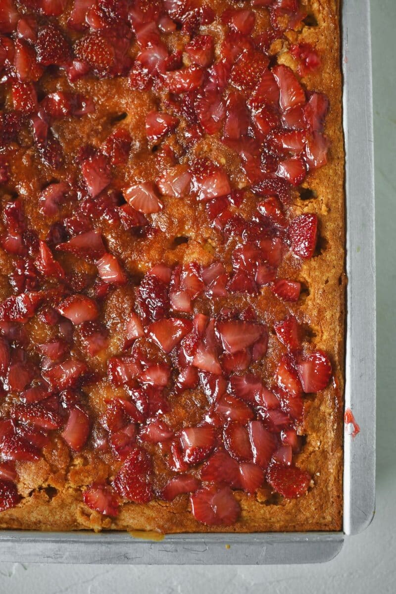 Spreading the cooked fresh strawberries over the poked cake.