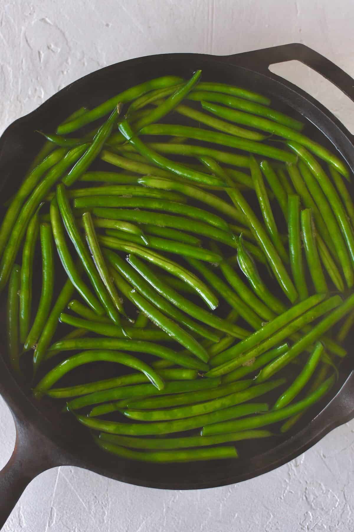 Boiling the green beans in the skillet before sauteing.
