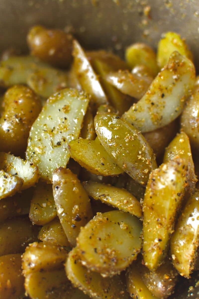 Seasoning halved potatoes with oil, salt, and garlic herb seasoning.