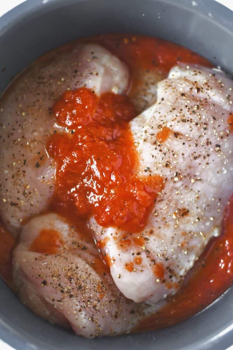 Seasoned Chicken, marinara and diced tomatoes add to the bowl of an instant pot.
