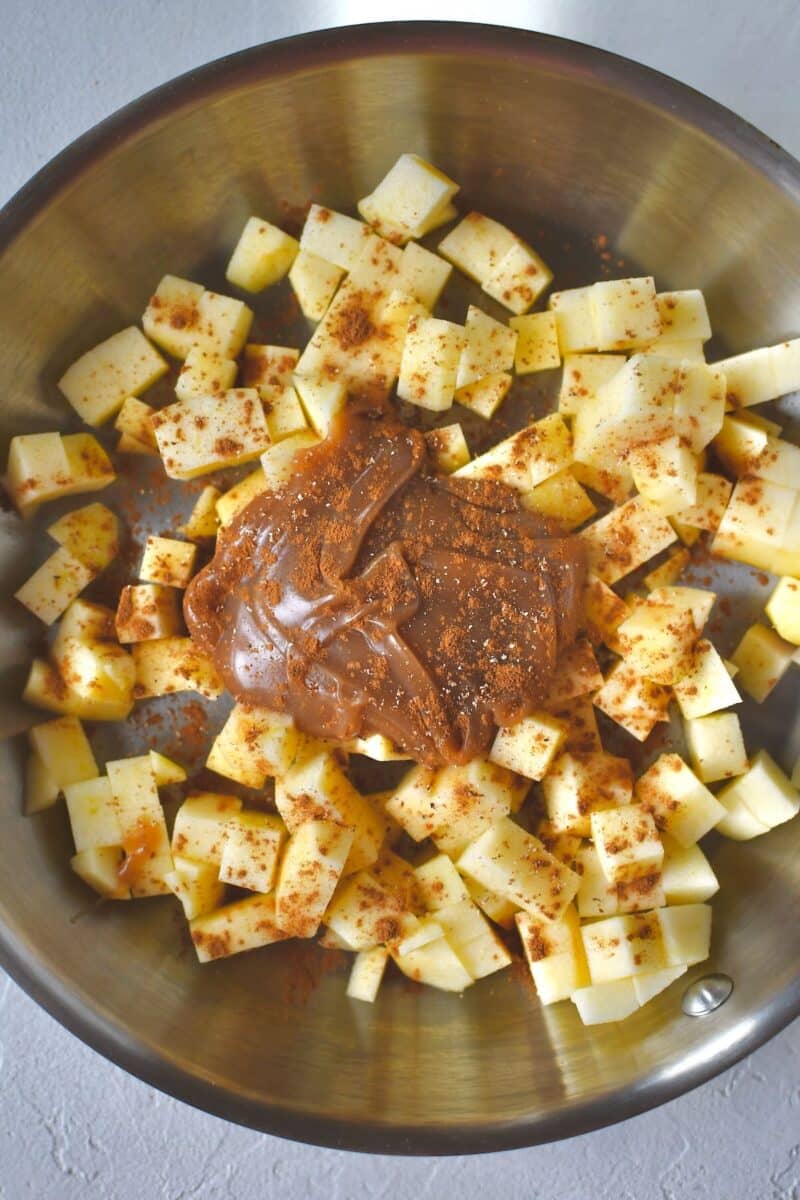 Diced fresh apples, caramel, and cinnamon in a skillet, before cooking.
