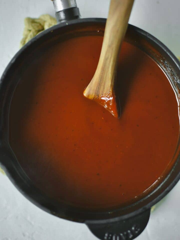 Finishes sauce in the saucepan with a spoon in it to stir.