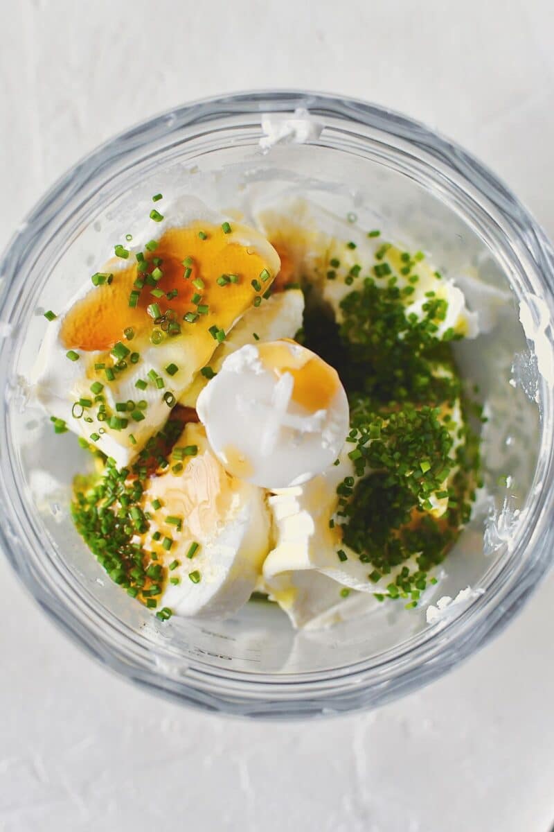 Goat cheese, cream cheese, wildflower honey, olive oil, chives, salt, and pepper, place in a mini food processor ready to be whipped.