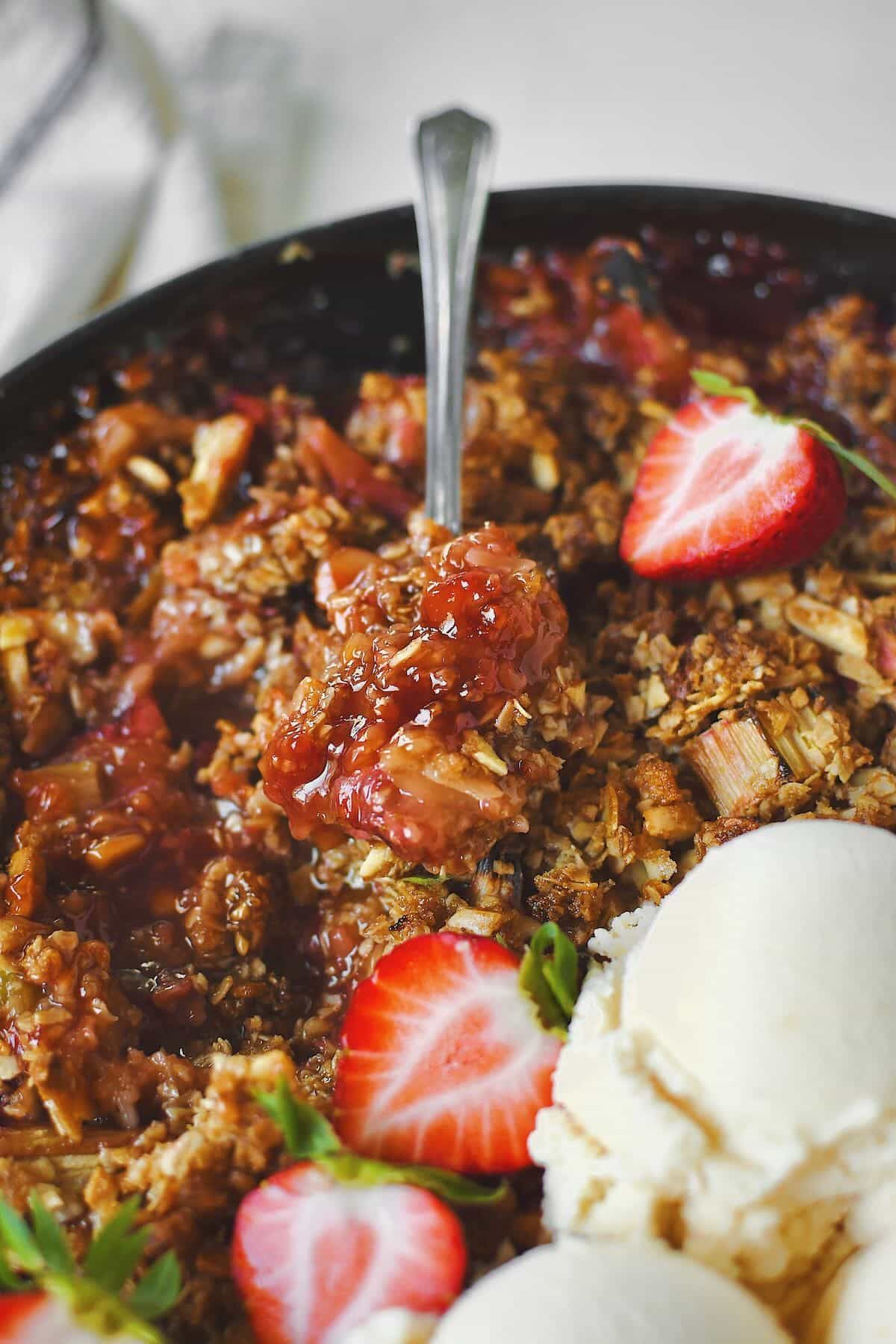 Strawberry Rhubarb Crisp, fresh from the oven and topped with fresh ice cream and sliced strawberries. Getting a first bite!