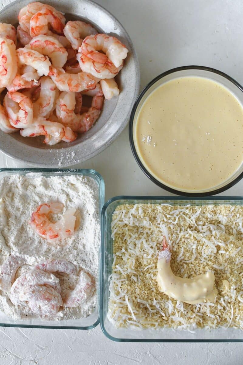 Dusting the shrimp in seasoned flour, then in batter, and coating in coconut panko.