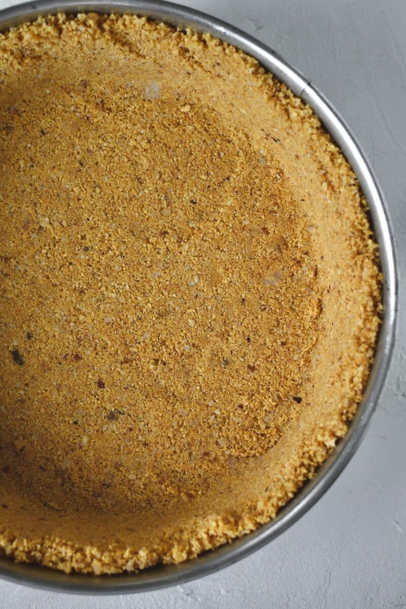 Hazelnut graham cracker crust pressed into a springform pan.