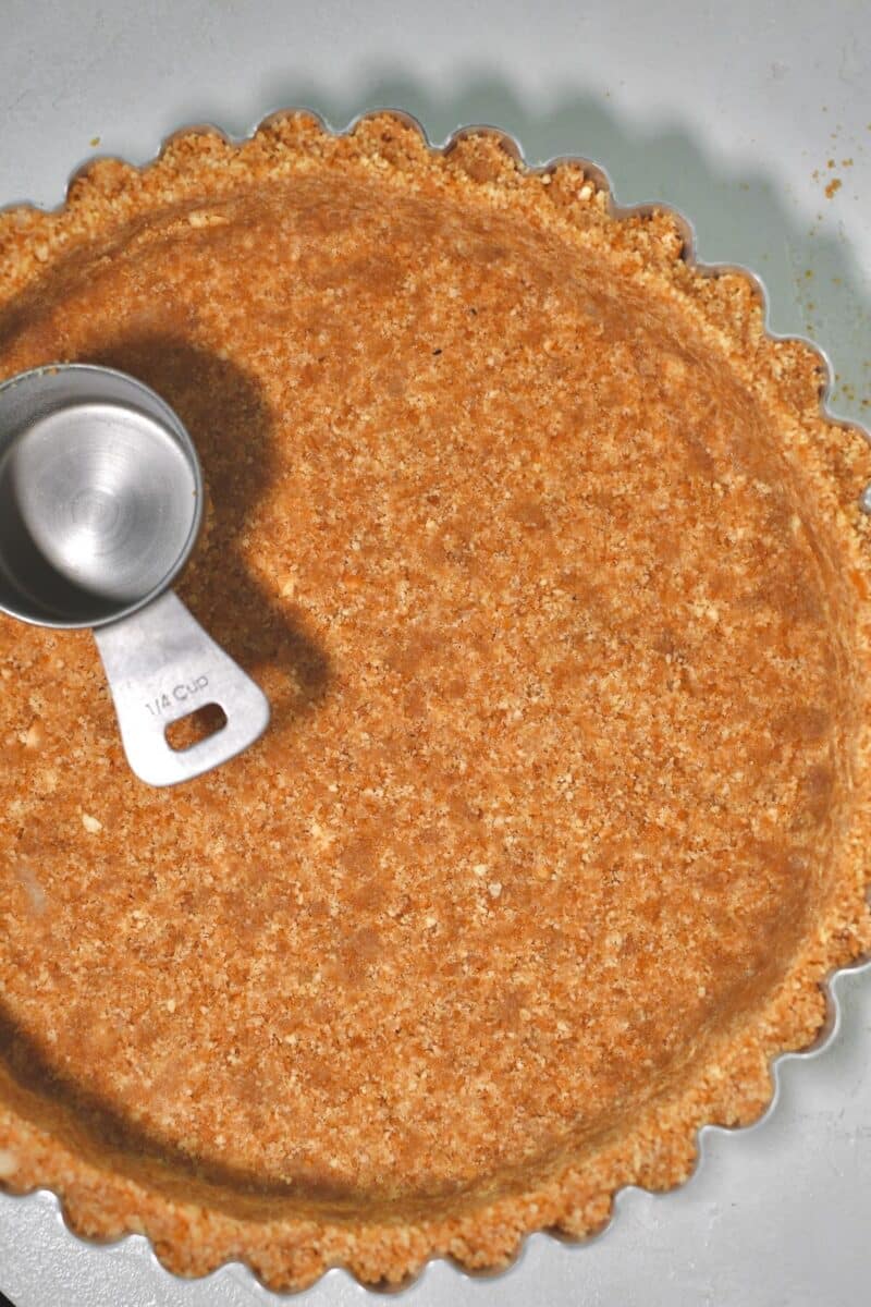 Firmly pressing the nilla wafer crust into a deep tart pan.