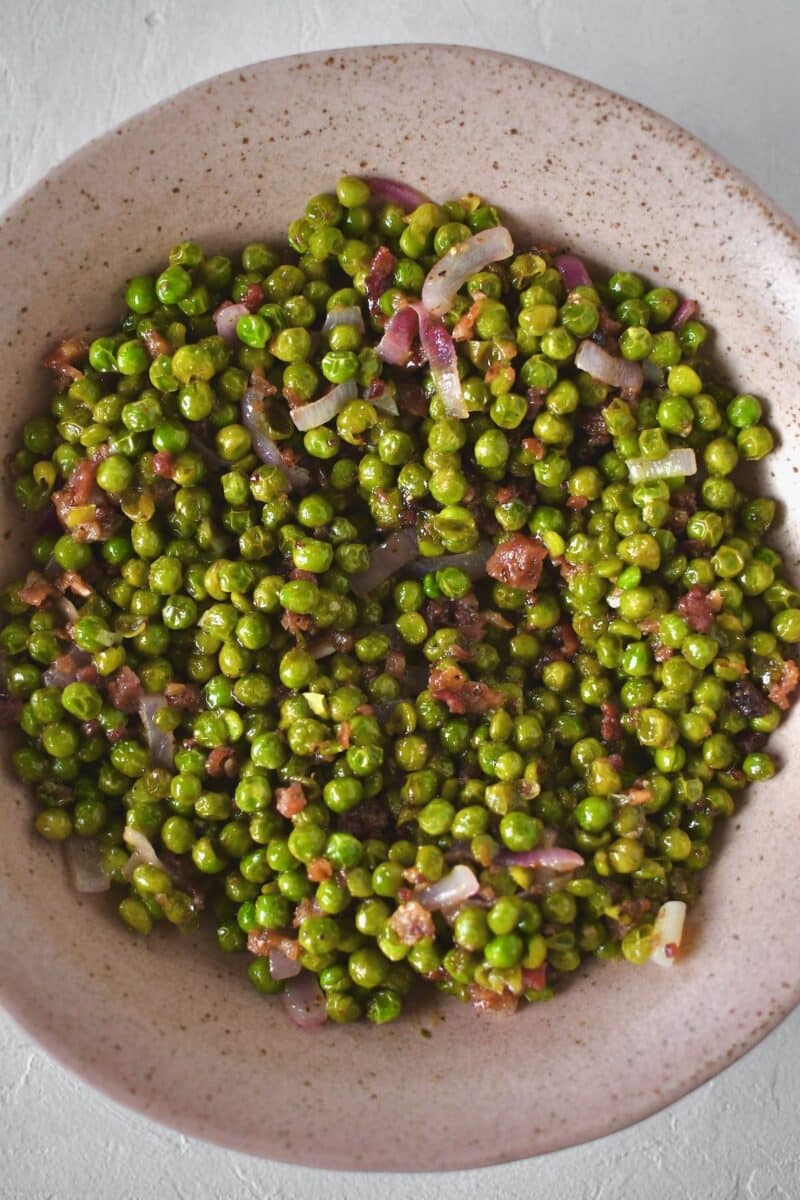 Peas in a serving dish after deglazing the saute pan with the vinaigrette.