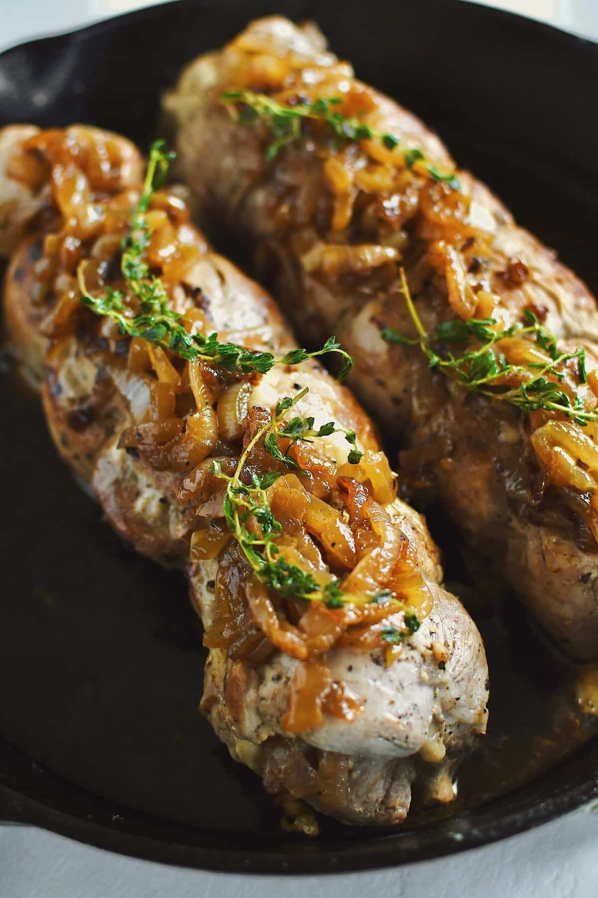 Stuffed Pork Tenderloins after searing and resting topped with extra onions and they thyme.